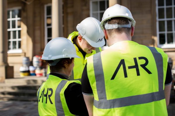 Three AHR colleagues on site in Huddersfield with high vis jackets and hard hats on.
