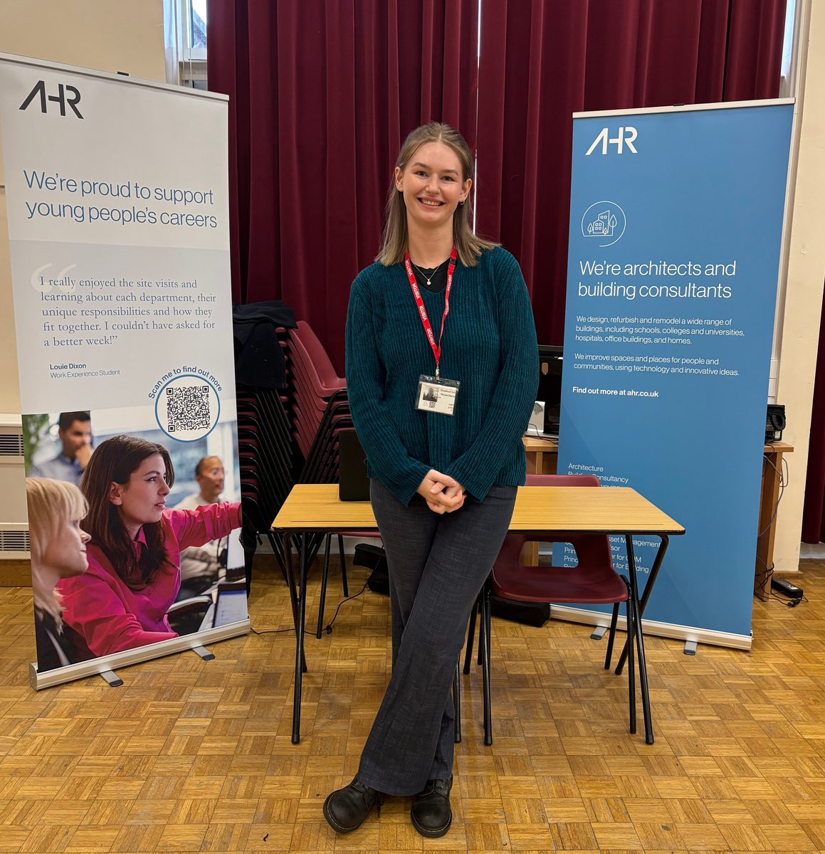 Building surveyor Nicole stood smiling in front of a stall at Broadoak School before speaking with students about career prospects.
