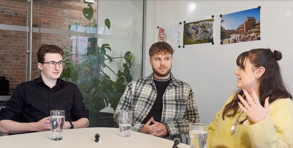 Three apprentices sit in a collaborative workspace discussing their experiences.
