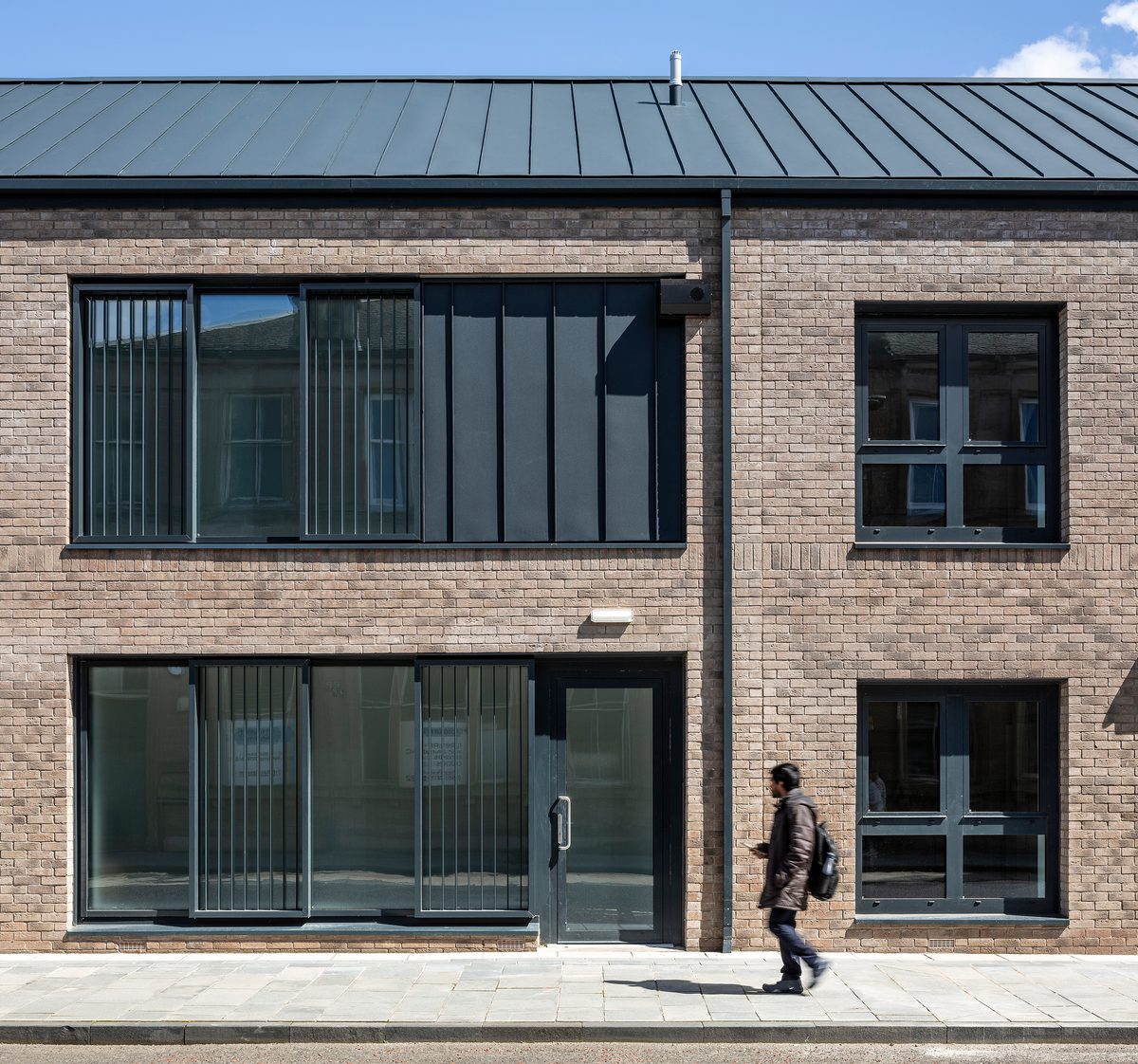An exterior view of the residential building showing its brickwork with a pedestrian walking in front on the pavement.