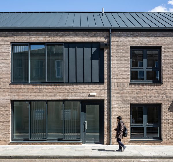 An exterior view of the residential building showing its brickwork with a pedestrian walking in front on the pavement.