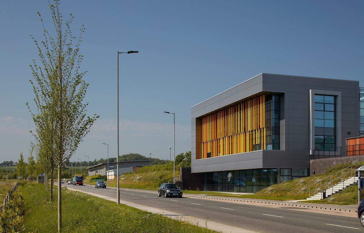 The grey and orange exterior of the AMP technology centre, with surrounding planting.