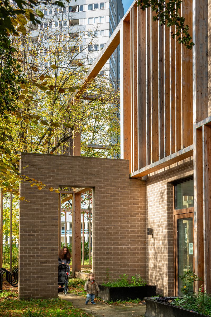 An elevation of Abbey Area Community Hub with a woman and child in the foreground approaching the building.