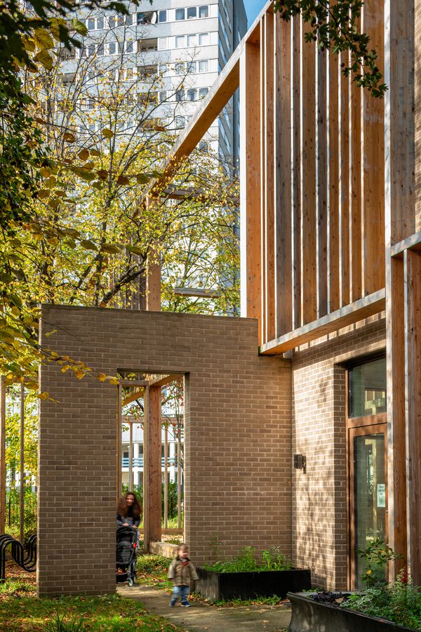 An elevation of Abbey Area Community Hub with a woman and child in the foreground approaching the building.