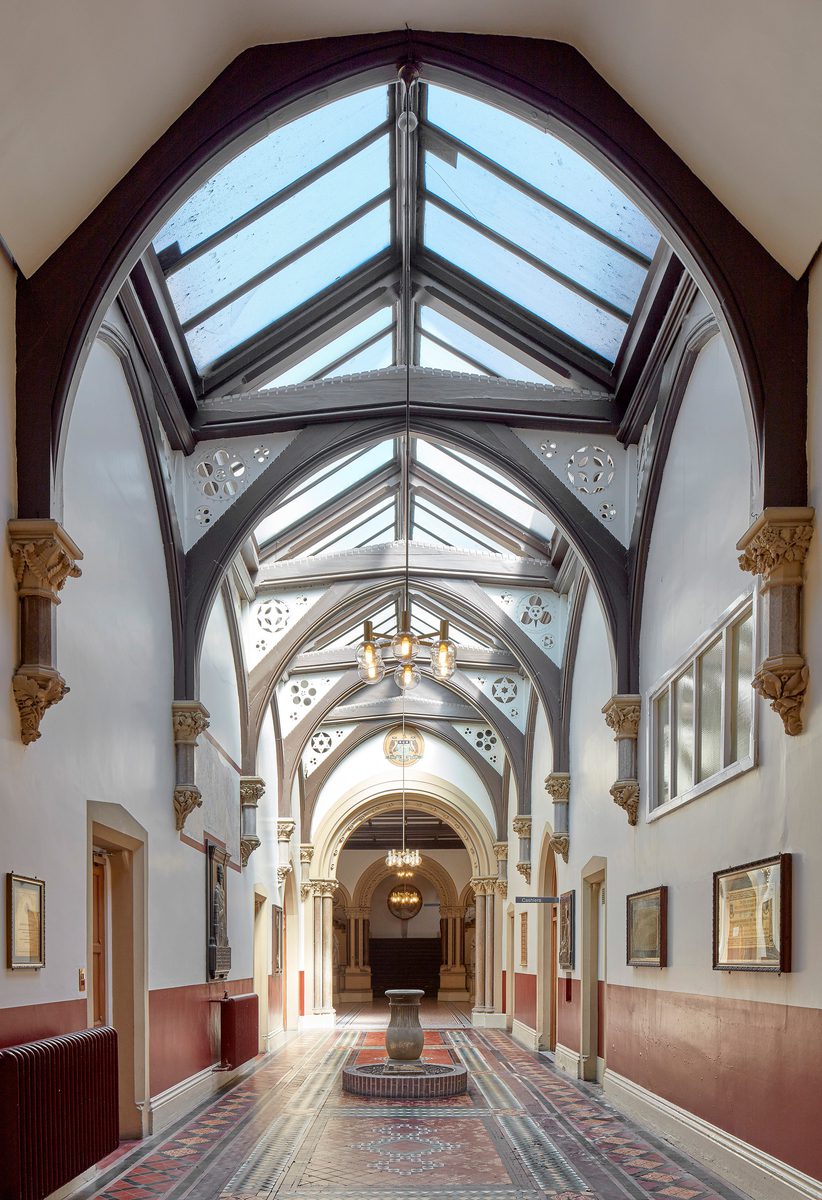 The bright reception of the Advanced Imaging Centre, with an extensively glazed ceiling providing ample natural light and ornate preserved historical features.
