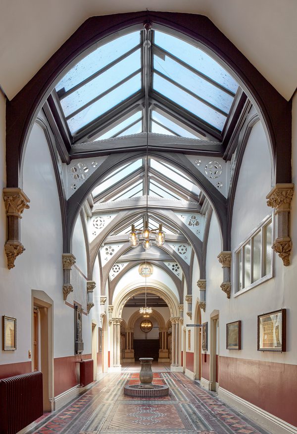 The bright reception of the Advanced Imaging Centre, with an extensively glazed ceiling providing ample natural light and ornate preserved historical features.