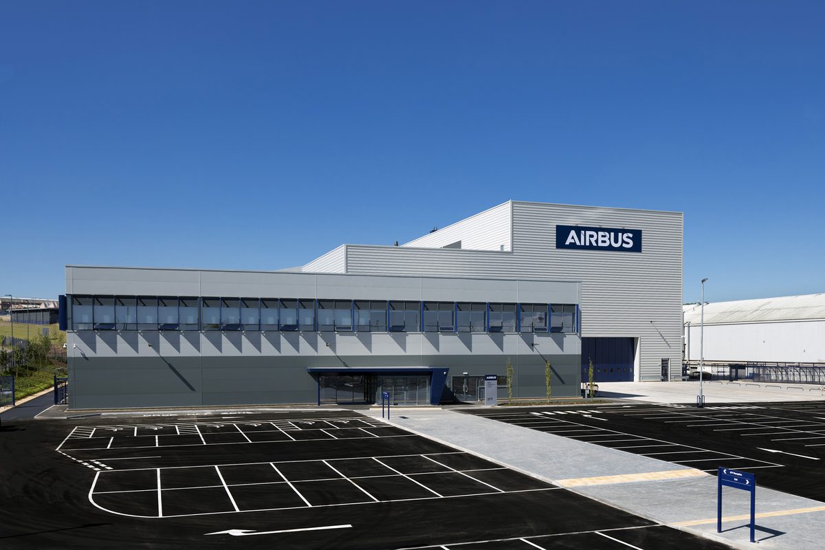 The grey exterior of Airbus Test & Research Facility showing the development in its entirety, with parking in front.