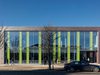 The leisure centre building elevation with trees and a car in the foreground on a bright, sunny day.