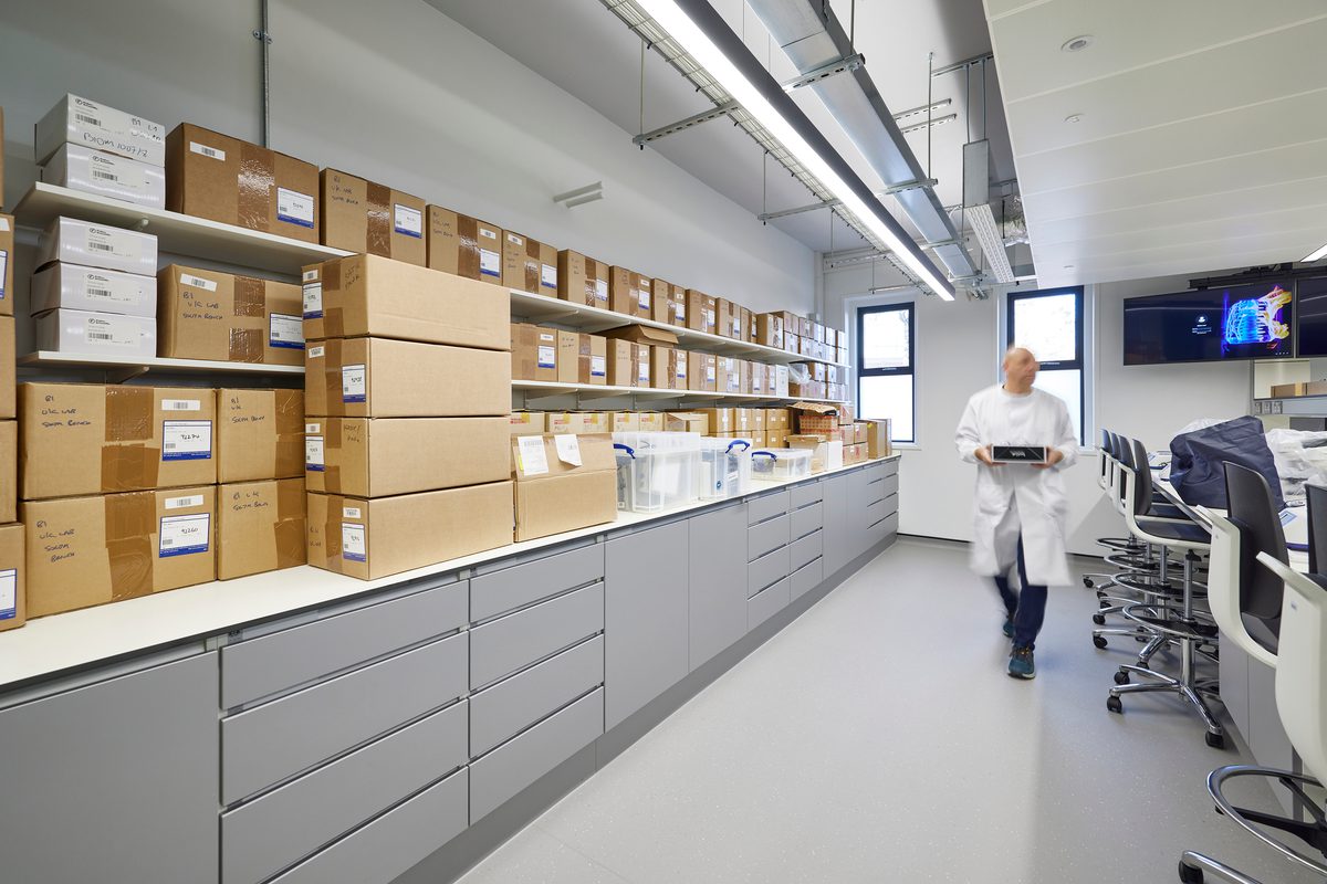 The brightly lit storage space inside the new laboratory with a person carrying resources across the room.
