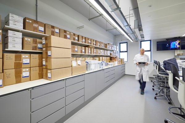 The brightly lit storage space inside the new laboratory with a person carrying resources across the room.