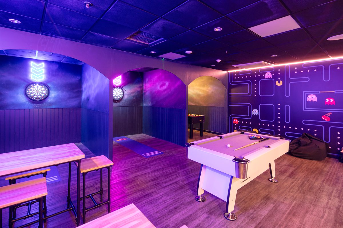The indoor darts and pool area of the Adventure Reef with pink and purple lights on.