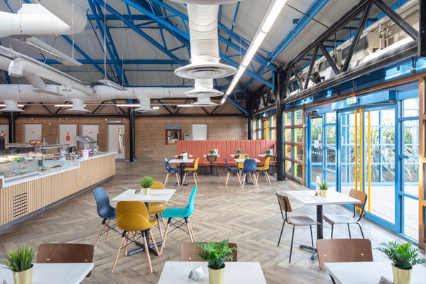The bright reception area within the refurbished Barnsley Metrodome, with café facilities, coloured detailing, floor to ceiling windows and exposed brickwork.