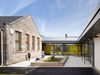 Children playing within the landscaped courtyard of Bent Primary School, surrounded by the historic stone building and newly created glazed circulation spaces.