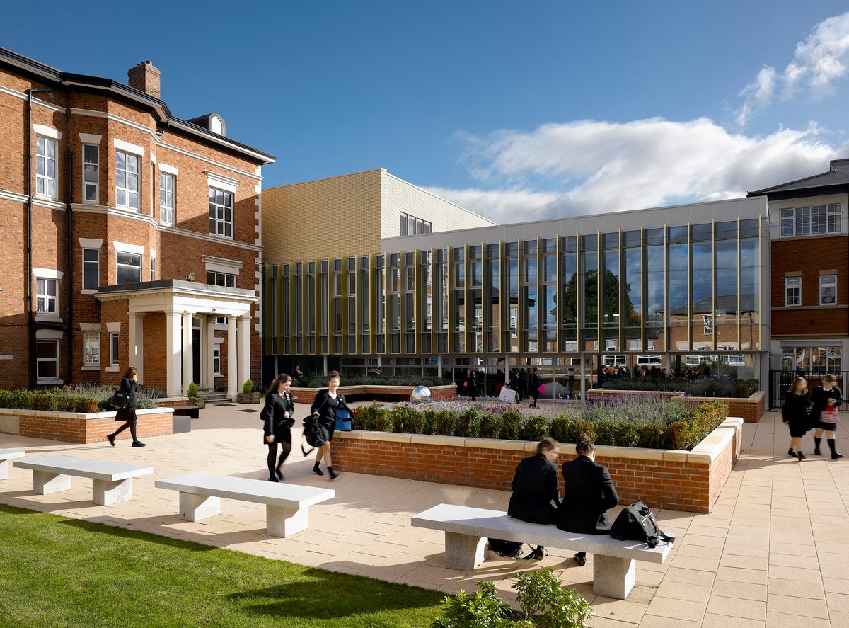 Students enjoying the outdoor courtyard of Birkenhead High School Academy, with the refurbished manor house to the left and adjoined new build part of the school to the right.
