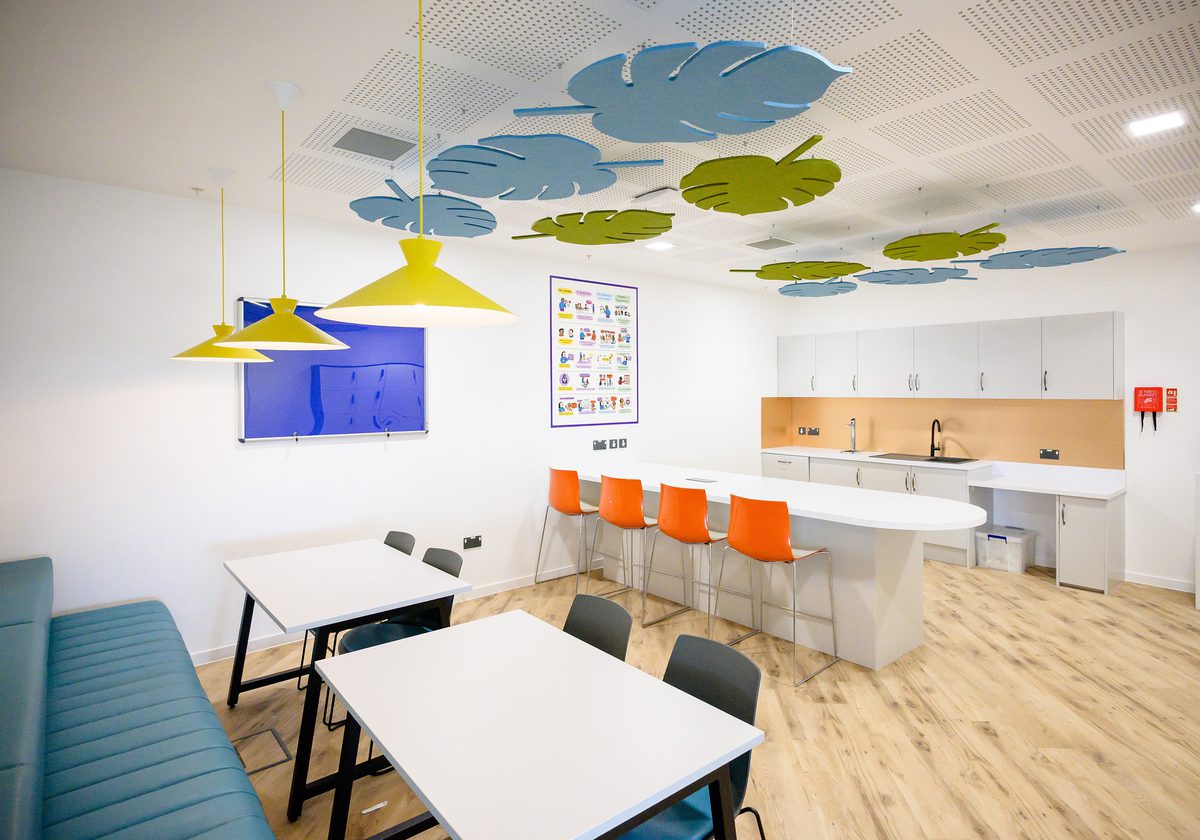 The bright, communal kitchen area within the Children and Family Court Advisory and Support Service office, with colourful furniture and fixtures.