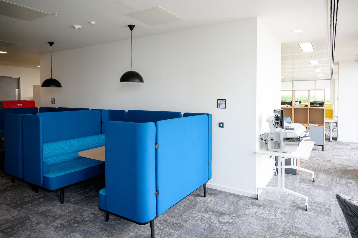 A private, bright blue seating booth surrounding a table within the open plan Children and Family Court Advisory and Support Service office.