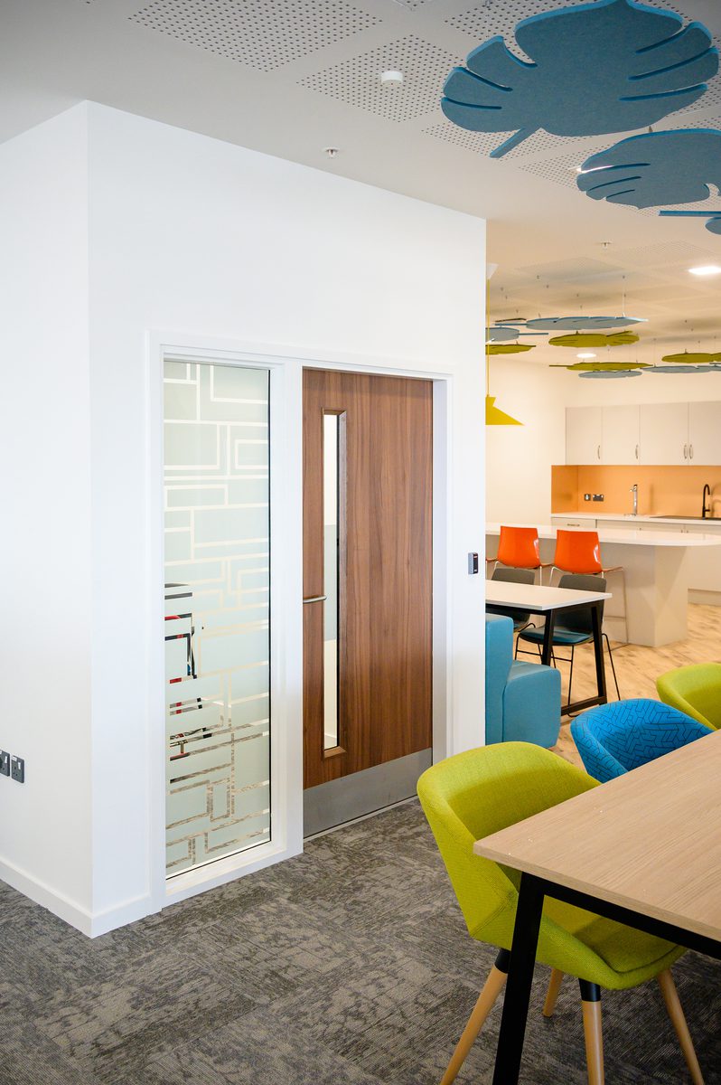 The bright, communal kitchen area within the Children and Family Court Advisory and Support Service office, with colourful furniture and fixtures.