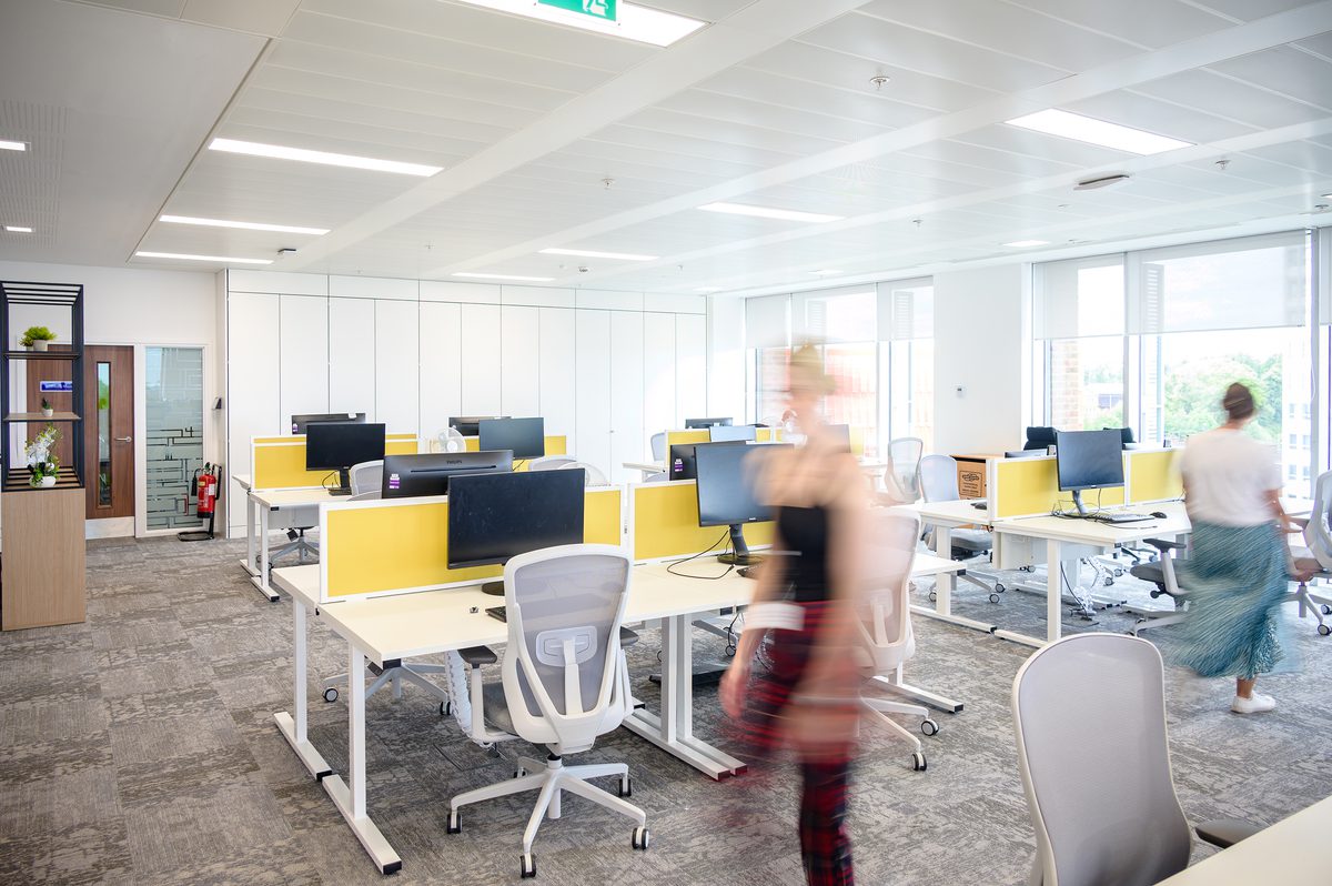 An internal shot of two people walking across the bright, open office space in Coventry.