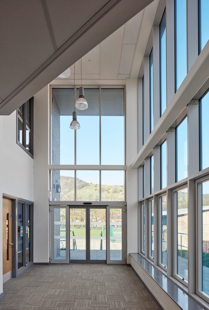An interior circulation space within Todmorden High School, part of Calderdale Council's property portfolio, with highly glazed walls, and scenic exterior views.