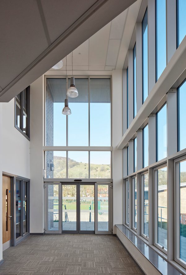 An interior circulation space within Todmorden High School, part of Calderdale Council's property portfolio, with highly glazed walls, and scenic exterior views.