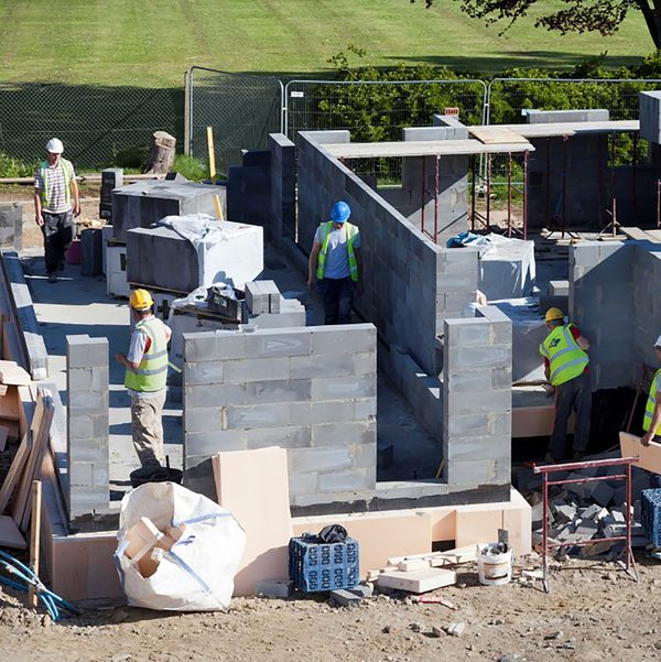 Construction workers on the building site of Cameron Close, with the houses under partial consturction.
