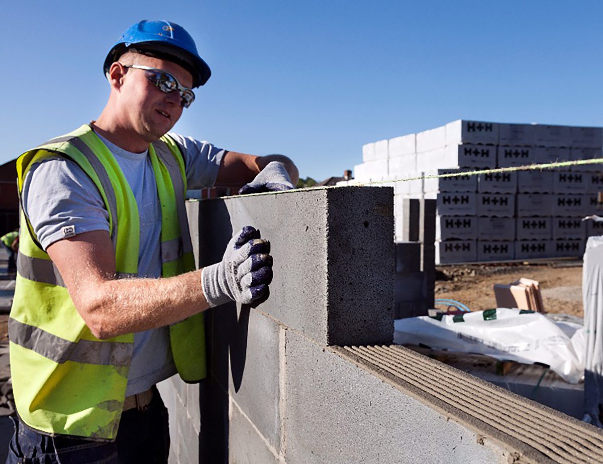 One construction worker adding a breeze block to a wall , of one of the houses under construction within the Cameron Close residential development.