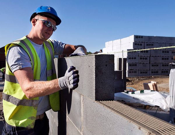 One construction worker adding a breeze block to a wall , of one of the houses under construction within the Cameron Close residential development.