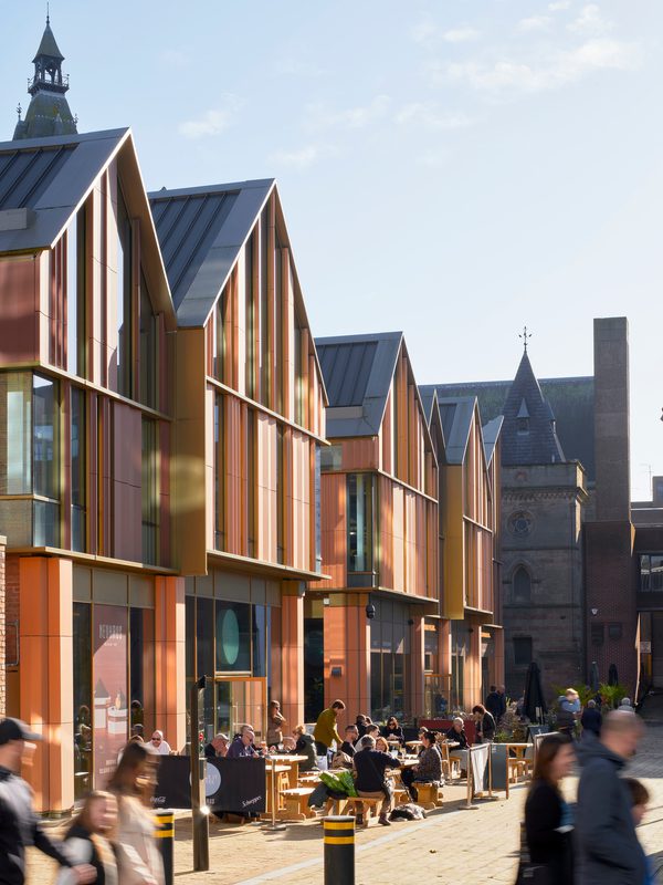 People sat outside in front of a new build section of Chester Northgate, enjoying a variety of activities within the shared public square.