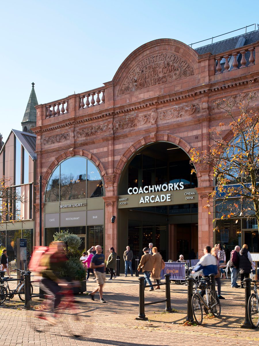 The preserved historic entrance of the Chester Northgate development, with people enjoying the new public realm in front.