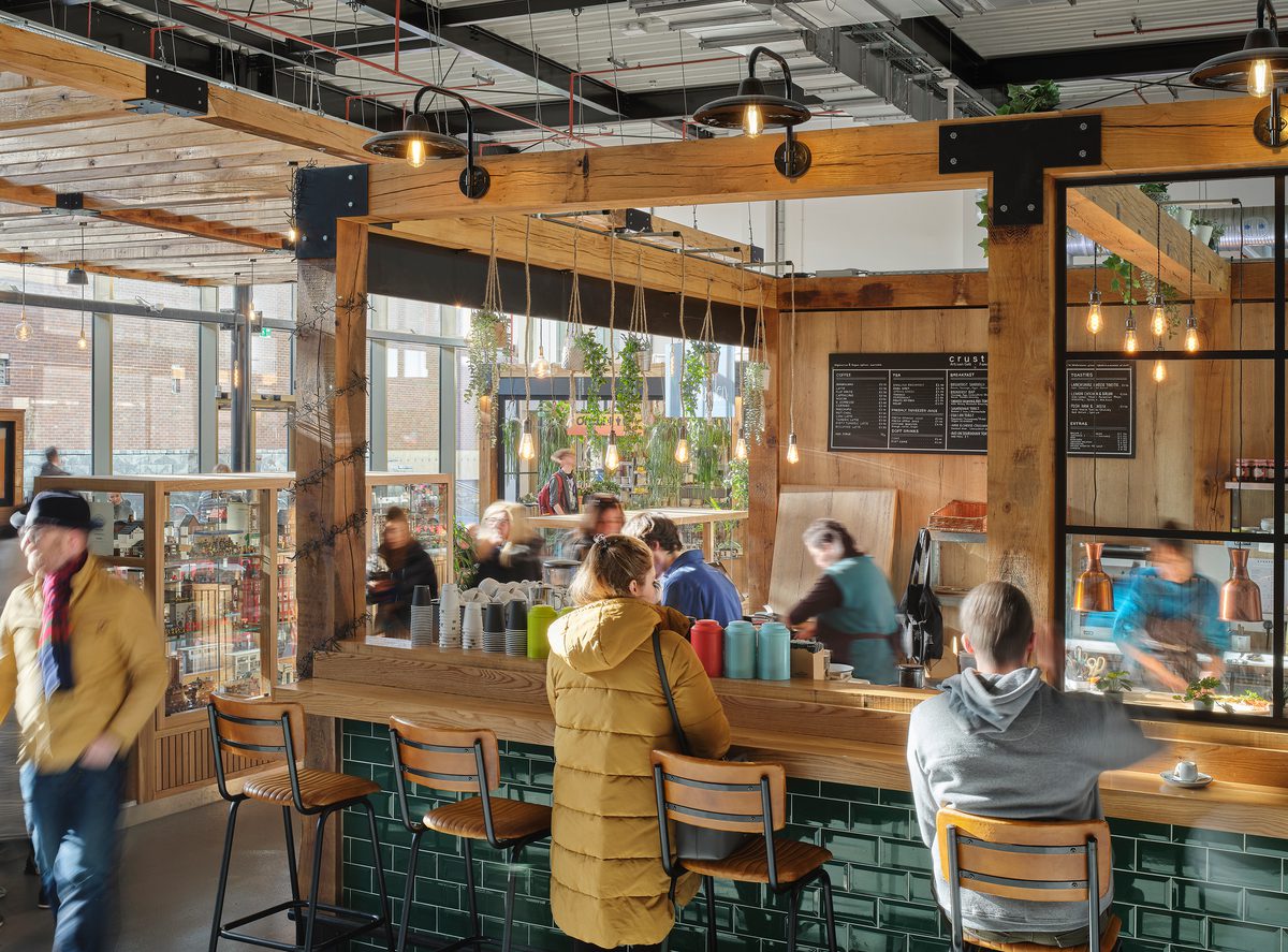 People enjoying one of the food and beverage vendors in the bright market hall, within the Chester Northgate development.