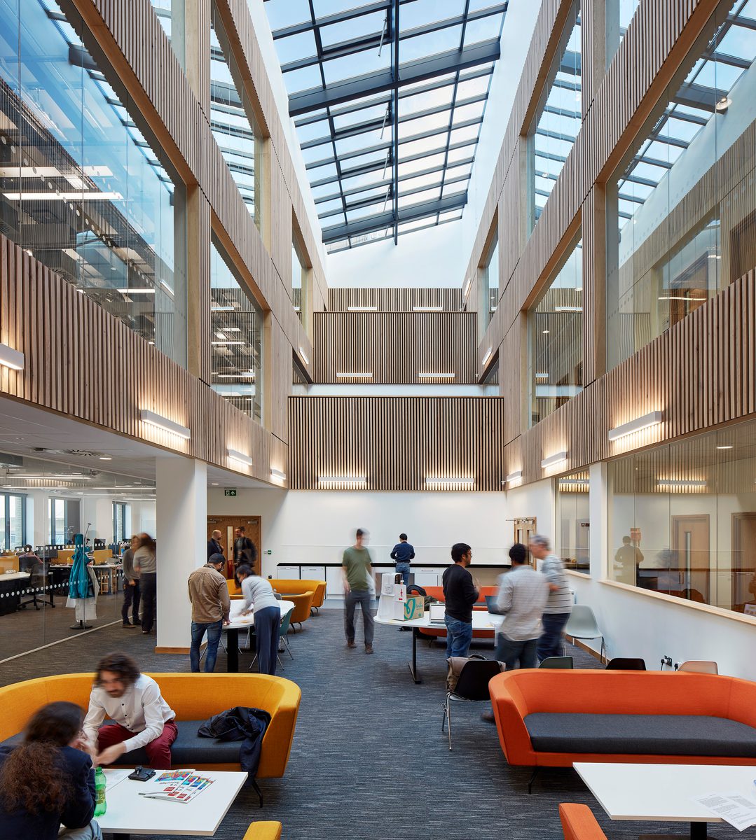 The bright central atrium in the Computational Foundry with collaborative workspaces, timber detailing and glazed roof.