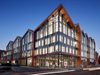 The glass fronted exterior of Conwy Council offices, showing its corner location and gabled roof at dusk.