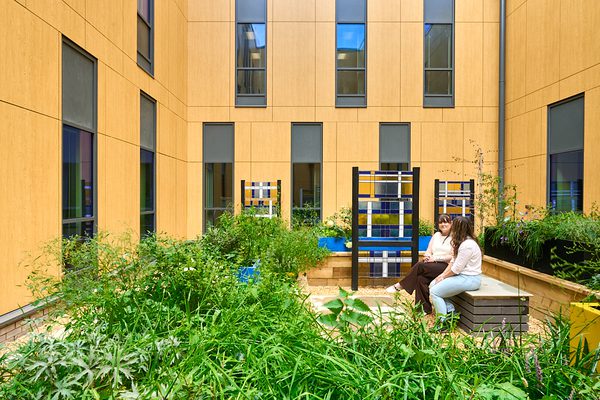 Two people sat in the outdoor courtyard with seating and plants.