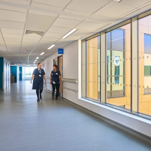 Staff members walking down a curved, well-lit circulation space within the Countess of Chester Hospital.