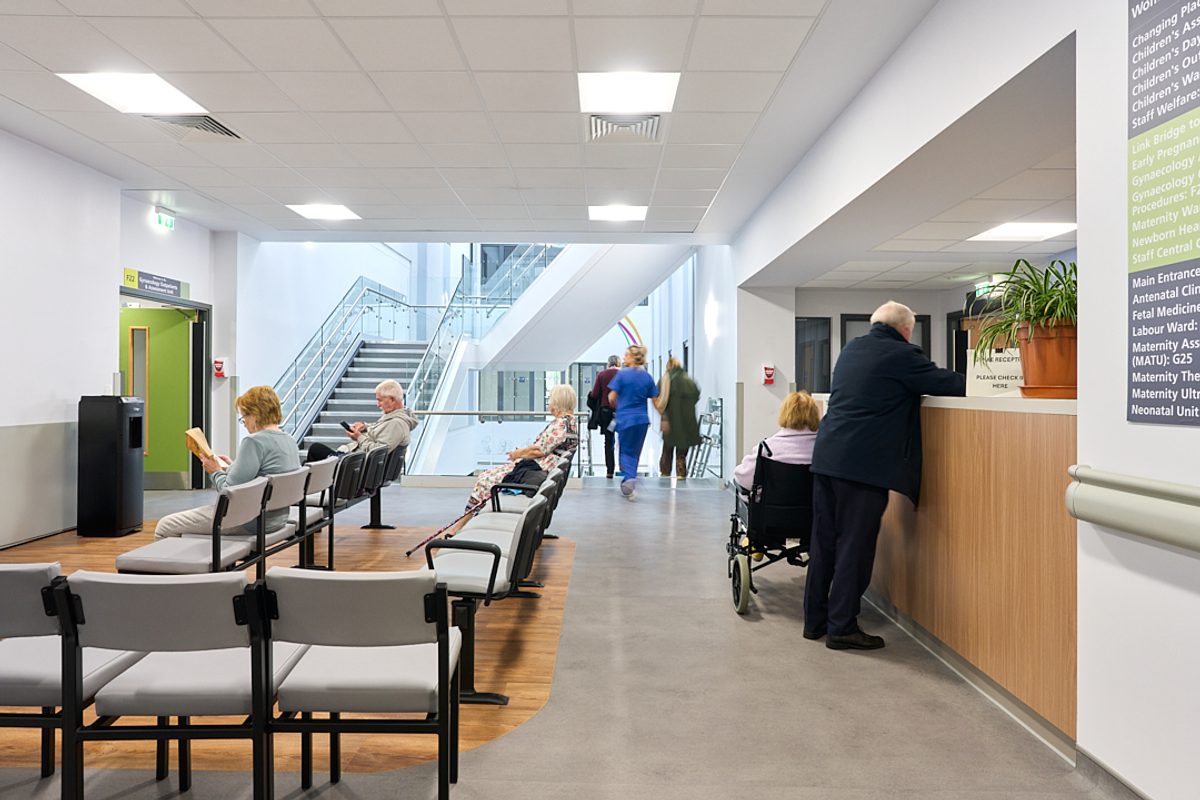People sitting and standing in one of the waiting areas in the Women and Children's Building.
