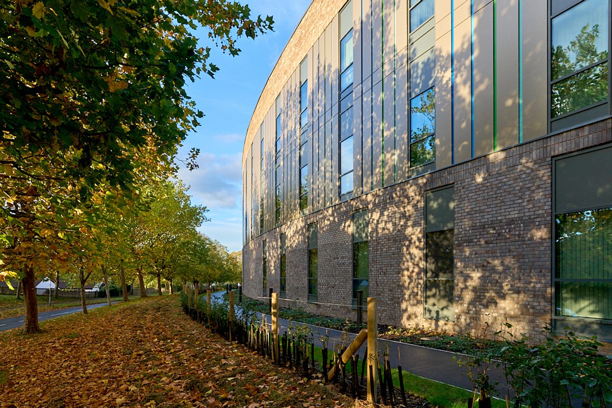 The curved edge of the Women and Children's Building surrounded by trees.