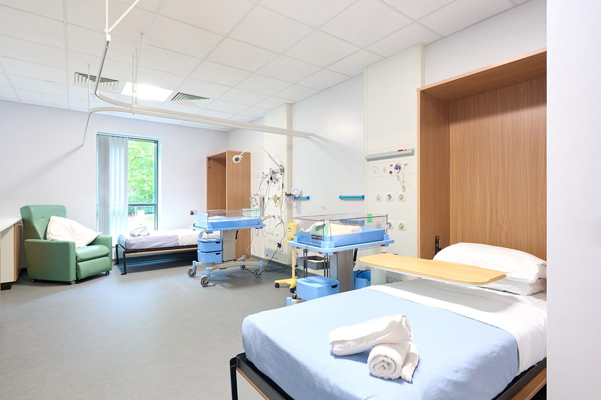 A maternity suite with a pull-down bed and comfortable chairs for visitors and family.