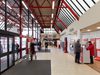 Pedestrians using the main entrance hall with glazed façade, roof lights and ticket machines, at Crewe Station.