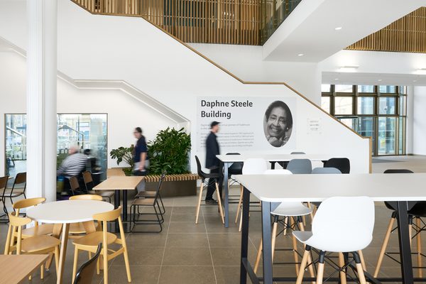 An interior of the cafe area inside the building, with the Daphne Steele mural in front and people interacting in the sociable space.