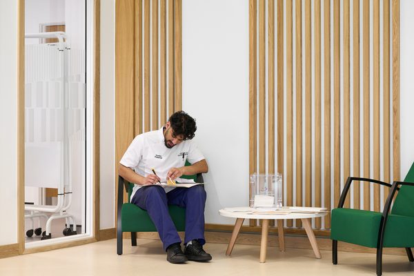 A member of staff sat down in the waiting area of the Podiatry clinic of the Daphne Steele Building.