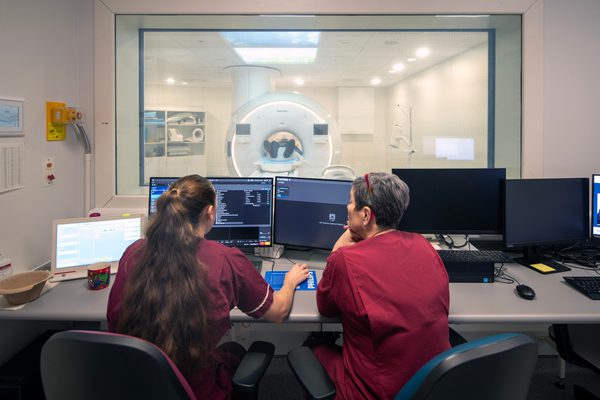 Two healthcare students sit at computers in a medical teaching space in the Emily Siddon Building, utilising innovative technology whilst learning.
