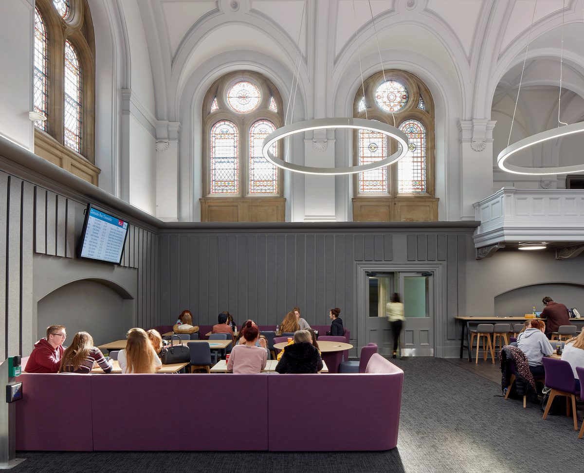 Students sitting within dining space in the refurbished Traders cafe in the Glenside Hub, with original stone features and windows and bright modern, bespoke lighting.