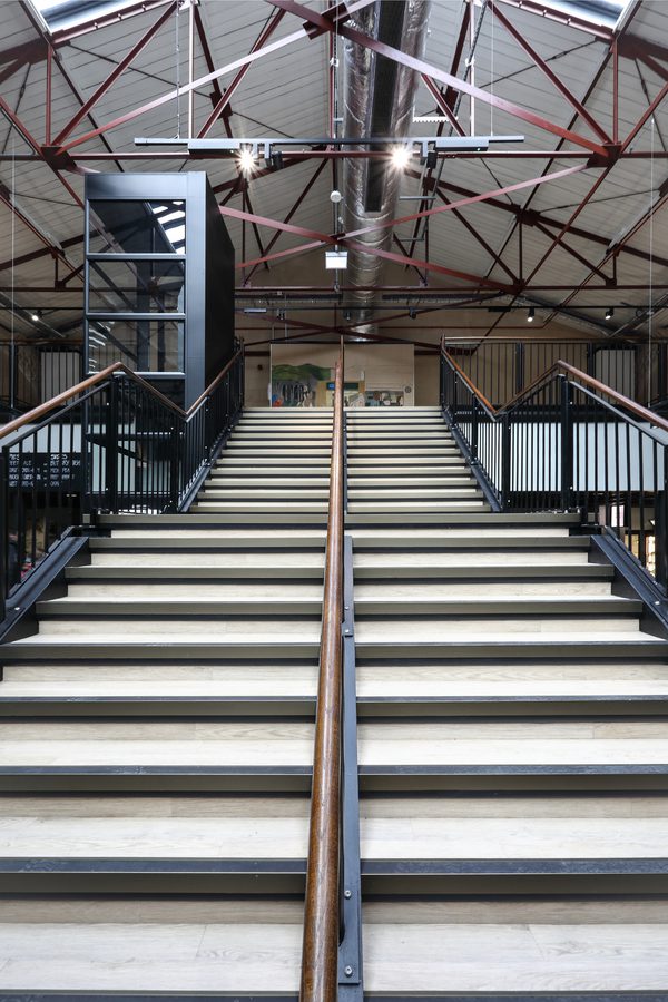 A tall portrait view of the grand staircase inside the Glossop Town and Market Hall.