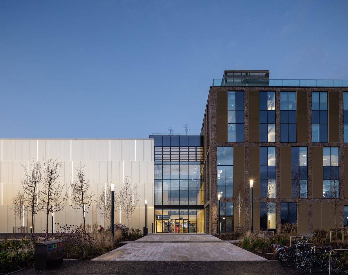 The striking exterior entrance to the East Quad building at dusk, with extensive glazing across the facade.