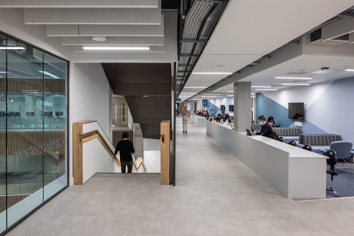 East Quad Building Distributed Learning Commons, adjacent to the stairs with students moving and using the different spaces.
