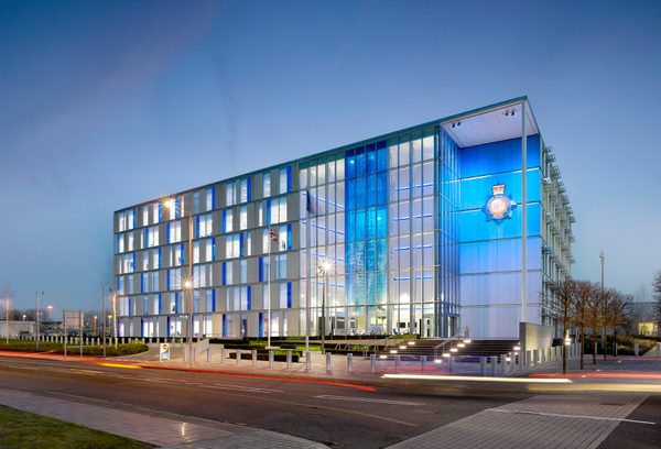Night view of Greater Manchester Police Force HQ with internal lighting illuminating the glazed facade.