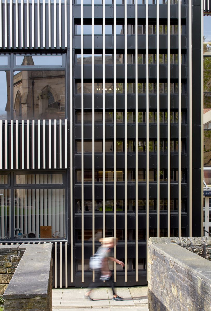 A detail image showing the bespoke exterior facade created as part of the refurbishment works of the Joseph Priestley Building, with a person walking in front of the building.