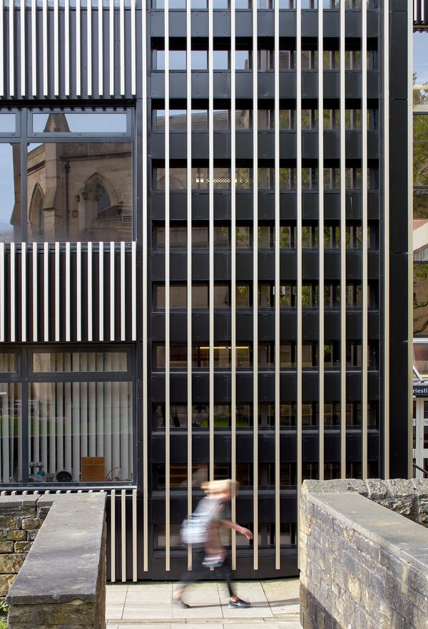 A detail image showing the bespoke exterior facade created as part of the refurbishment works of the Joseph Priestley Building, with a person walking in front of the building.
