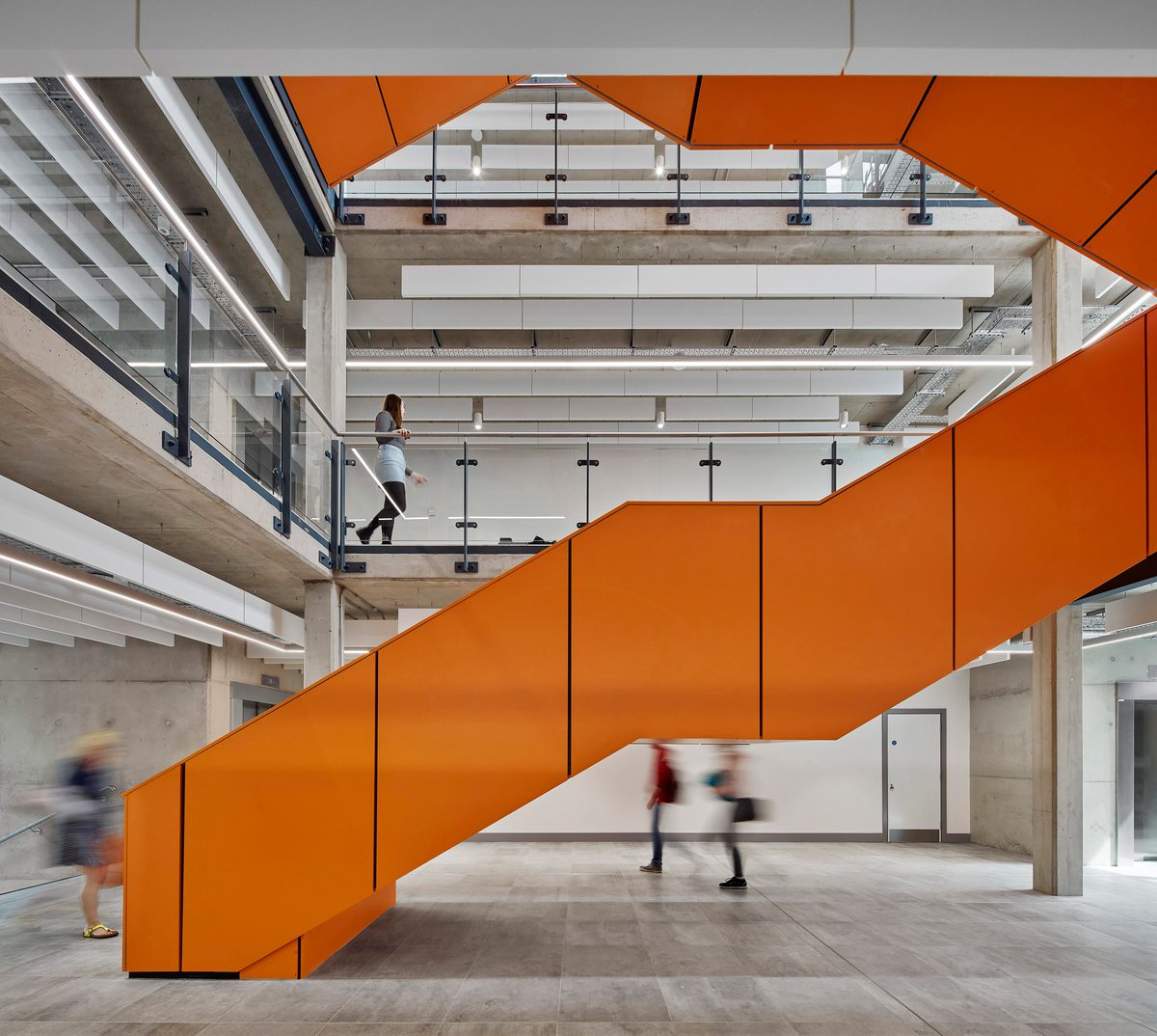 A striking orange staircase in a bright central area , with mezzanine balconies around the edge, created as part of the refurbishment works of the Joseph Priestley Building.