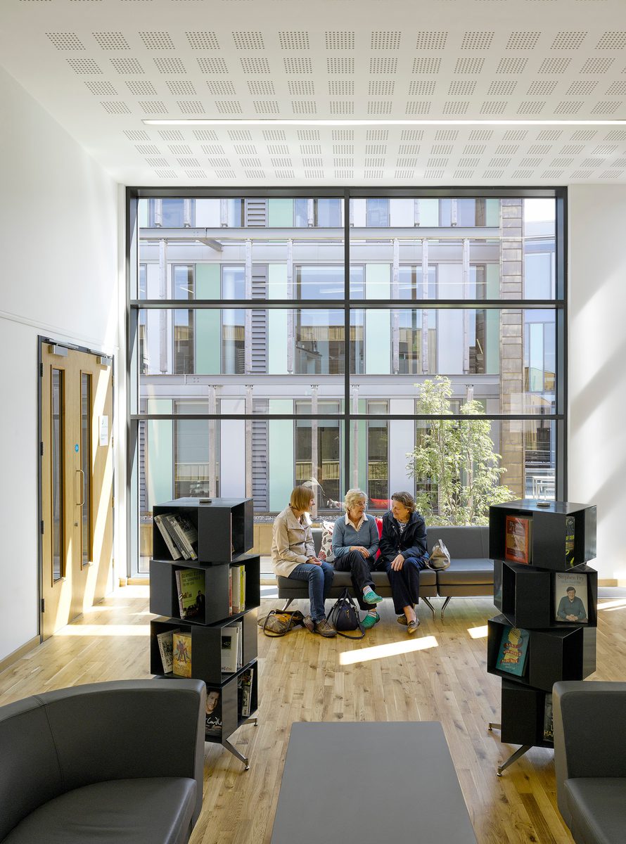 People seated in the library space within Keynsham Civic Centre and One-Stop-Shop, with large floor to ceiling windows behind.